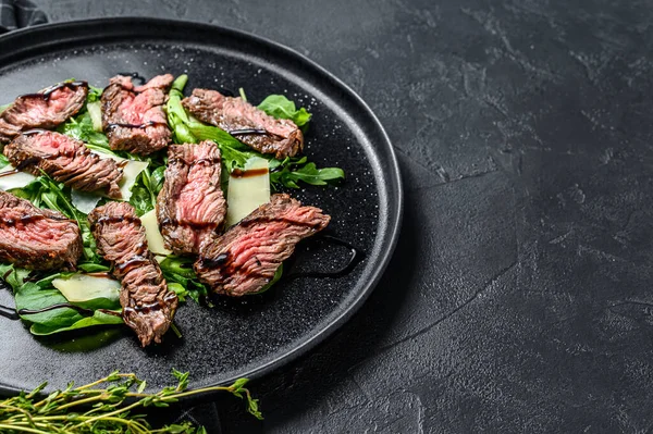 Ispanaklı biftek salatası, roka ve dilimlenmiş biftek. Siyah arka plan. Üst Manzara. Boşluğu kopyala — Stok fotoğraf