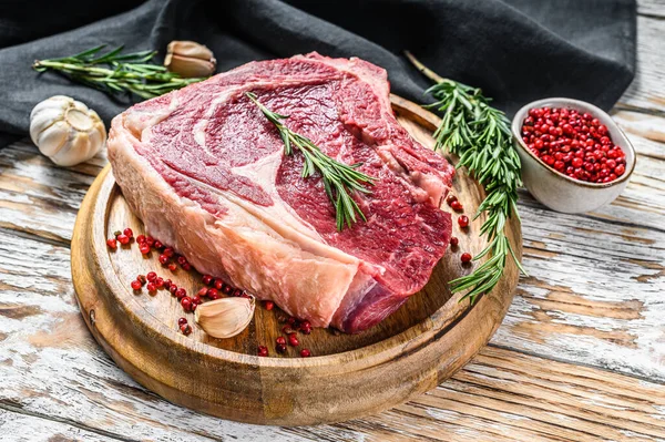 Kemiğe pirzola ya da kovboy bifteği. Çiğ Dallas bifteği. Beyaz ahşap arka plan. Üst görünüm