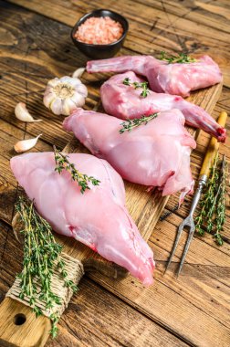 Kesme tahtasında çiğ tavşan bacağı. Ahşap arka plan. Üst görünüm