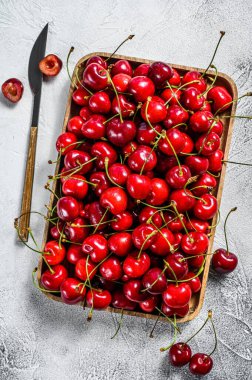 Tahta bir kasede kirazlar. Taze kirazlar. Gri arka plan. Üst görünüm