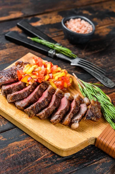 Bife grelhado com tampa de rampa numa tábua de corte. Fundo de madeira escuro. Vista superior — Fotografia de Stock