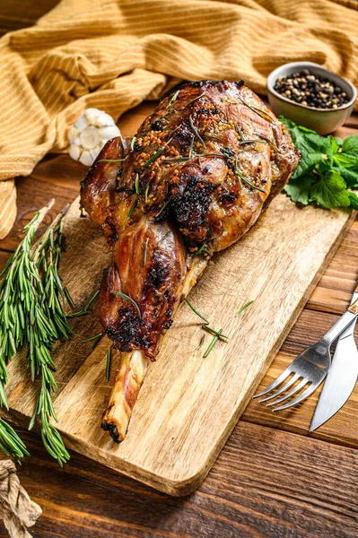 Roasted goat leg with herbs. Farm meat. Wooden background. Top view. Copy space — Stock Photo, Image