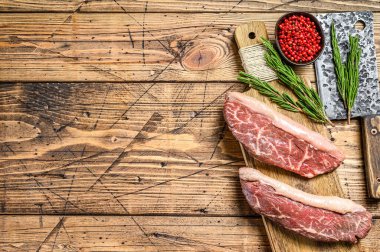 Raw rump cap steak on a chopping Board. wooden background. Top view. Copy space clipart