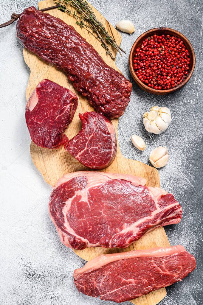 Variety of raw black angus beef meat steaks fillet Mignon, rib eye or cowboy, Striploin or new york, skirt or machete. White background. Top view