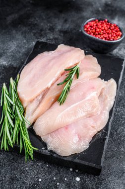 Misket tahtasında çiğ tavuk göğsü fileto bifteği. Siyah arka plan. Üst görünüm