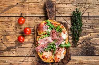 Jambonlu jambonlu dilimlenmiş pizza, roka ve ahşap tahtada parmesan peyniri. Ahşap arka plan. Üst görünüm