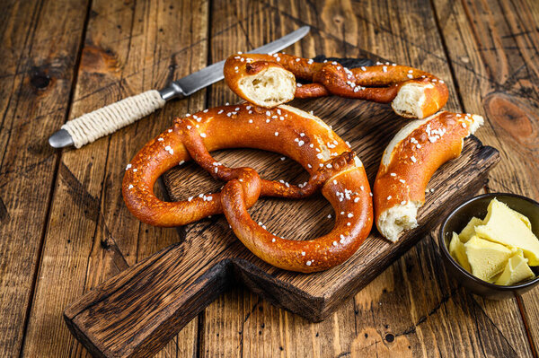 Baked pretzels with sea salt on a rustic wooden cutting board. Wooden background. Top view