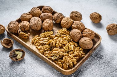 Tahta tabakta ceviz ve ceviz çekirdeği. Gri arka plan. Üst görünüm