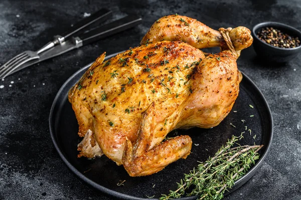 Homemade whole baked chicken rotisserie with thyme. Black background. Top view