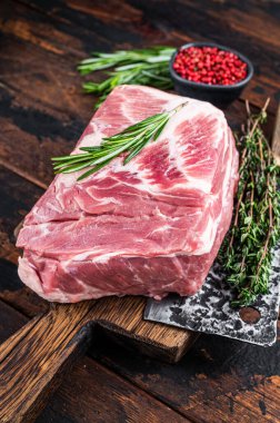 Kasap satırıyla ahşap kesme tahtasındaki taze pirzola biftekleri için domuz boyunlu çiğ et. Koyu ahşap arka plan. Üst görünüm