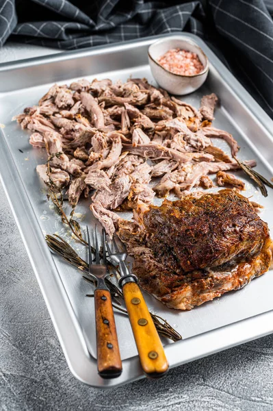 Bbq grilled puilled pork meat in a steel baking tray. White background. Top view