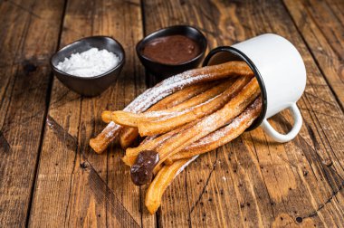 Şeker ve çikolata soslu Churros. Ahşap arka plan. Üst görünüm