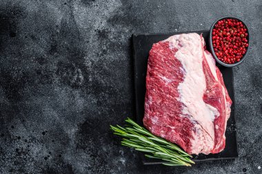 Mermer bir tahtanın üzerinde kesilmiş çiğ biftek. Siyah arka plan. Üst Manzara. Boşluğu kopyala