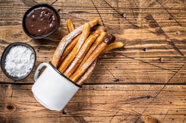 Şeker ve çikolata soslu Churros. Ahşap arka plan. Üst Manzara. Boşluğu kopyala