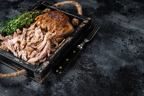 Bbq slow roast puilled pork meat in a wooden tray. Black background. Top view. Copy space