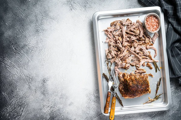 Texas bbq smoked puilled pork meat in a steel baking tray. White background. Top view. Copy space