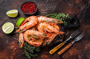 Kesme tahtasındaki dev karides ve şifalı bitkiler. Karanlık arka plan. Üst görünüm