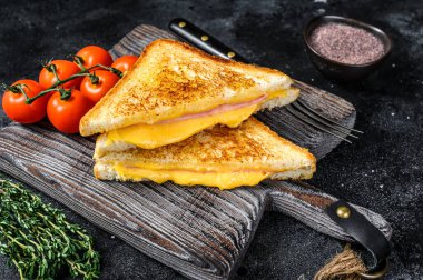 Kesme tahtasında ızgara jambonlu ve peynirli sandviç. Siyah arka plan. Üst görünüm