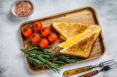 Kesme tahtasında ev yapımı kızarmış jambonlu ve peynirli sandviç. Beyaz arka plan. Üst görünüm