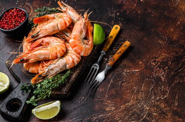 Kesme tahtasındaki dev karides ve şifalı bitkiler. Karanlık arka plan. Üst Manzara. Boşluğu kopyala