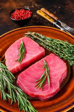 Biberiyeli çiğ ton balığı filetosu ve kekik. Karanlık arka plan. Üst görünüm