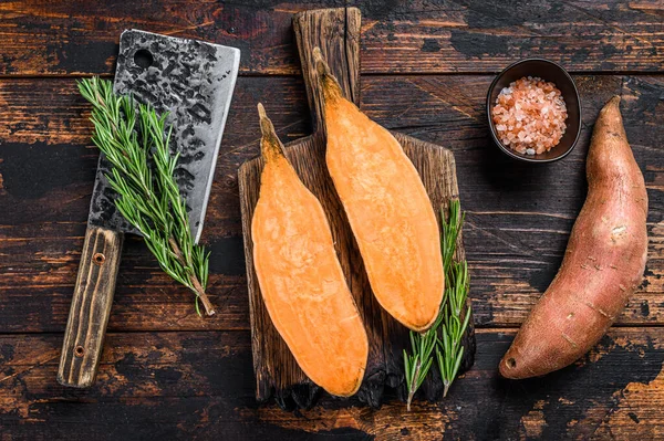 Raw cut Sweet potato on Wooden cutting board. Dark wooden background. Top view