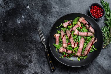 Izgara biftek salatası, roka, nar ve sebze. Siyah arka plan. Üst Manzara. Boşluğu kopyala