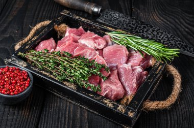 Çiğ doğranmış domuz eti, kırsal tepside baharatlı et. Siyah ahşap arka plan. Üst görünüm