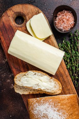 Tahta kesme tahtasının üzerinde tereyağı ve yiyecek parçaları. Karanlık arka plan. Üst görünüm