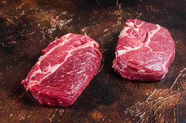 Kasap masasında çiğ Chuck gözü etli biftek. Karanlık arka plan. Üst görünüm