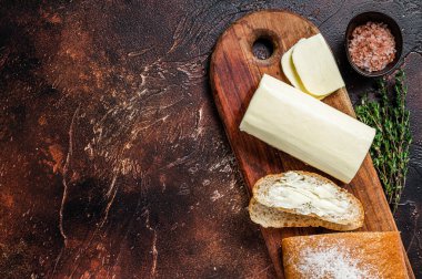 Tahta kesme tahtasına tereyağlı dilimlenmiş tost ekmeği. Karanlık arka plan. Üst Manzara. Boşluğu kopyala