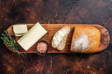 Tahta kesme tahtasına tereyağlı dilimlenmiş tost ekmeği. Karanlık arka plan. Üst görünüm