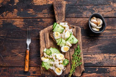 Karidesli sandviç, karides, bıldırcın yumurtası ve çavdar ekmekli salatalık. Karanlık ahşap arka plan. en üstteki görünüm.