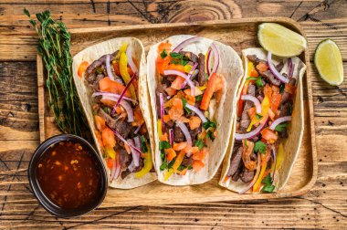 Biftek, soğan, domates, tatlı biber ve salsa soslu taco. Meksika yemeği. Ahşap arka plan. Üst görünüm.