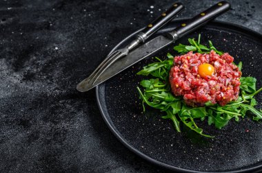 Roka ve bıldırcın yumurtalı sığır eti. Siyah arka plan. Üst Manzara. Boşluğu kopyala.