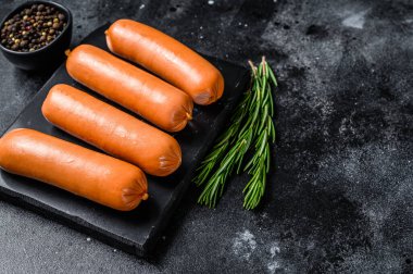 Mermer bir tahtanın üzerinde çiğ sosisli sucuk. Siyah arka plan. Üst Manzara. Boşluğu kopyala.