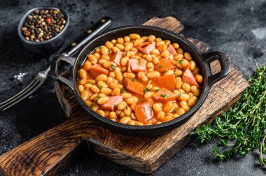 Tavada füme sosis ve domates soslu haşlanmış böbrek fasulyesi. Siyah arka plan. Üst Manzara. Boşluğu kopyala.