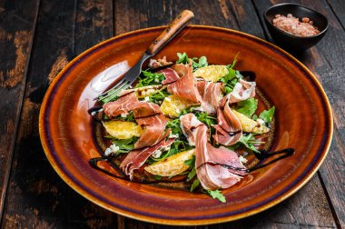 Jambonlu salata, parmesan peyniri, roka ve mandalina. Karanlık ahşap arka plan. Üst görünüm.