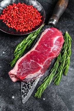 Bıçağın üstünde çiğ mermer biftek. Siyah arka plan. Üst görünüm.