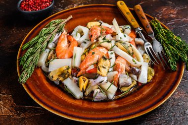 Karides, karides, midye, mürekkep balığı ve ahtapotlu deniz ürünleri kokteyli. Koyu ahşap arka plan. Üst görünüm.