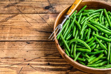 Ahşap tabakta pişmiş yeşil fasulye. Ahşap arka plan. Üst Manzara. Boşluğu kopyala.