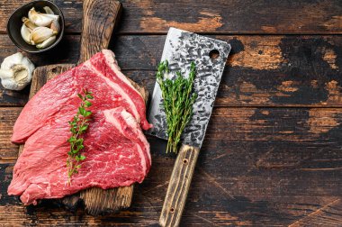 Kesme tahtasının üzerinde çiğ et, pirzola ve biftek. Koyu ahşap arka plan. Üst Manzara. Boşluğu kopyala.