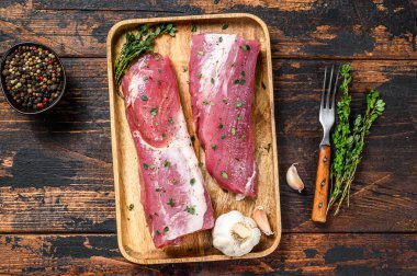 Terbiye edilmiş domuz filetosu ve kekik bifteği. Koyu ahşap arka plan. Üst görünüm.