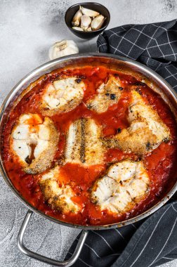 Fırında pişirilmiş makrozor beyaz balığı ve tavada domates. Beyaz tahta arka plan. Üst görünüm.