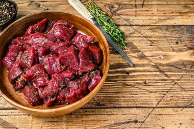 Çiğ geyik eti, tahtadan bir tabakta gulaş için kesilmiş. Ahşap arka plan. Üst Manzara. Boşluğu kopyala.