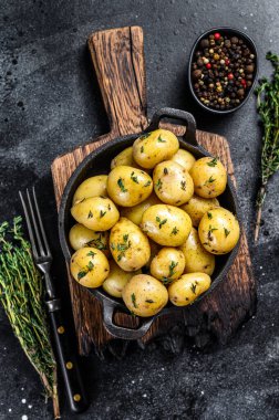 Küçük bebek tavada tereyağlı haşlanmış patates. Siyah arka plan. Üst görünüm