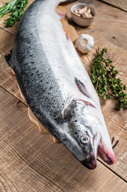 Tahta bir kichen masasında otlarla birlikte çiğ somon balığı. Ahşap arka plan. Üst görünüm