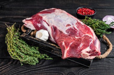 Tahta tepside kekik ile taze çiğ kuzu eti. Siyah ahşap arka plan. Üst görünüm