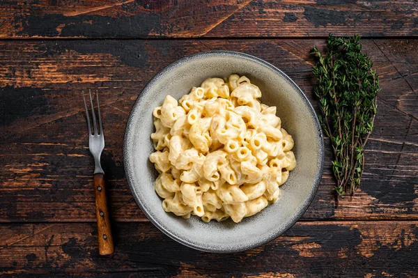 American dish Mac and cheese macaroni pasta with Cheddar. Dark wooden background. Top view