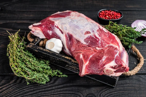 Tahta tepside kekik ile taze çiğ kuzu eti. Siyah ahşap arka plan. Üst görünüm